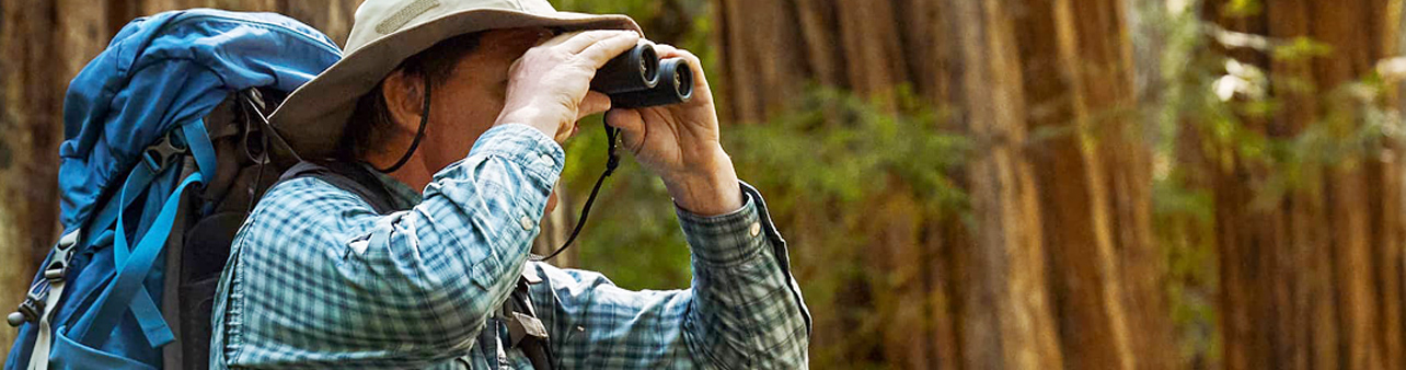 man holding binoculars in the woods